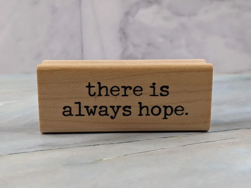 A rubber stamp mounted on a wooden block with the words "there is always hope."