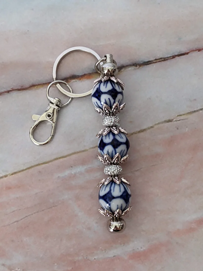 A beaded bag charm with blue and white porcelain beads paired with silver metal findings.