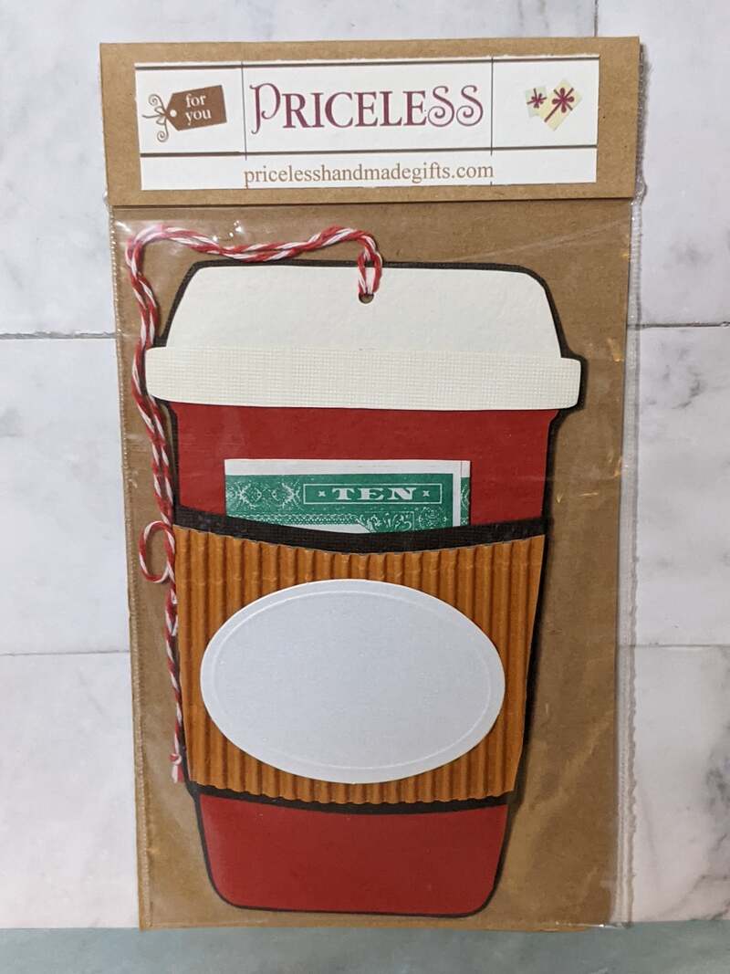 A gift card holder that is shaped like a to-go coffee cup that has a pocket to hold cash or a gift card.
