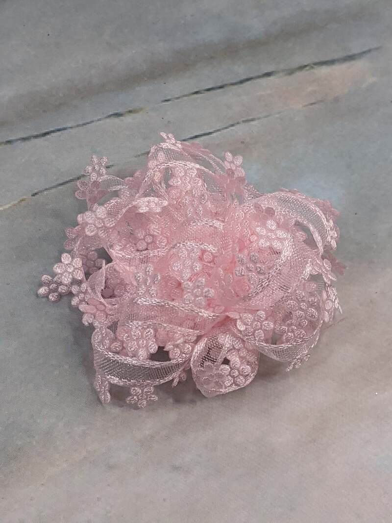 A pink handmade reusable gift bow that easily clips onto a wrapped present.