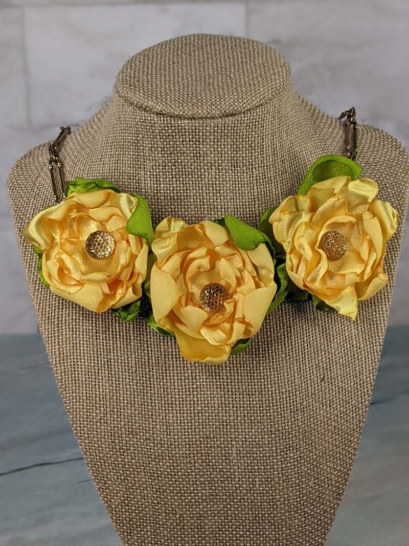Beautiful yellow handmade satin flowers are featured on this large link chain necklace in antique gold.