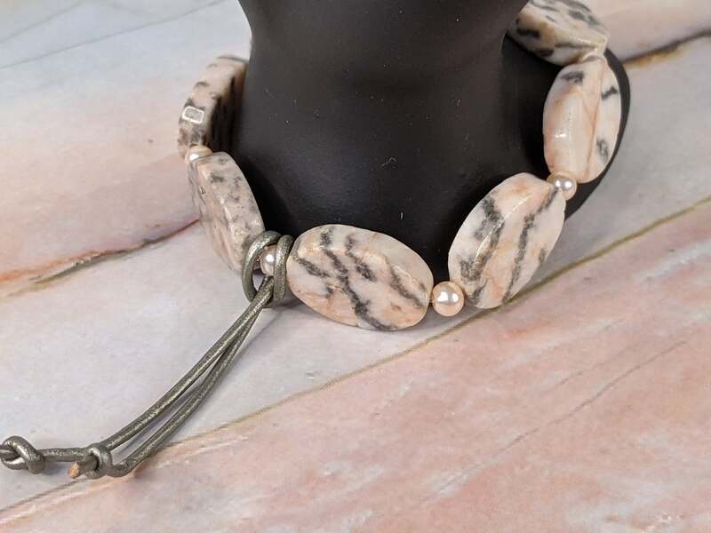 A beautiful stretch bracelet with pink and gray natural zebra stone beads, small glass pearls, and a leather cord decoration.