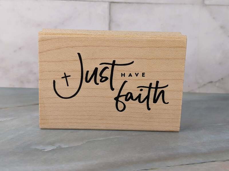 A rubber stamp mounted on a wooden block that says, "Just have faith."